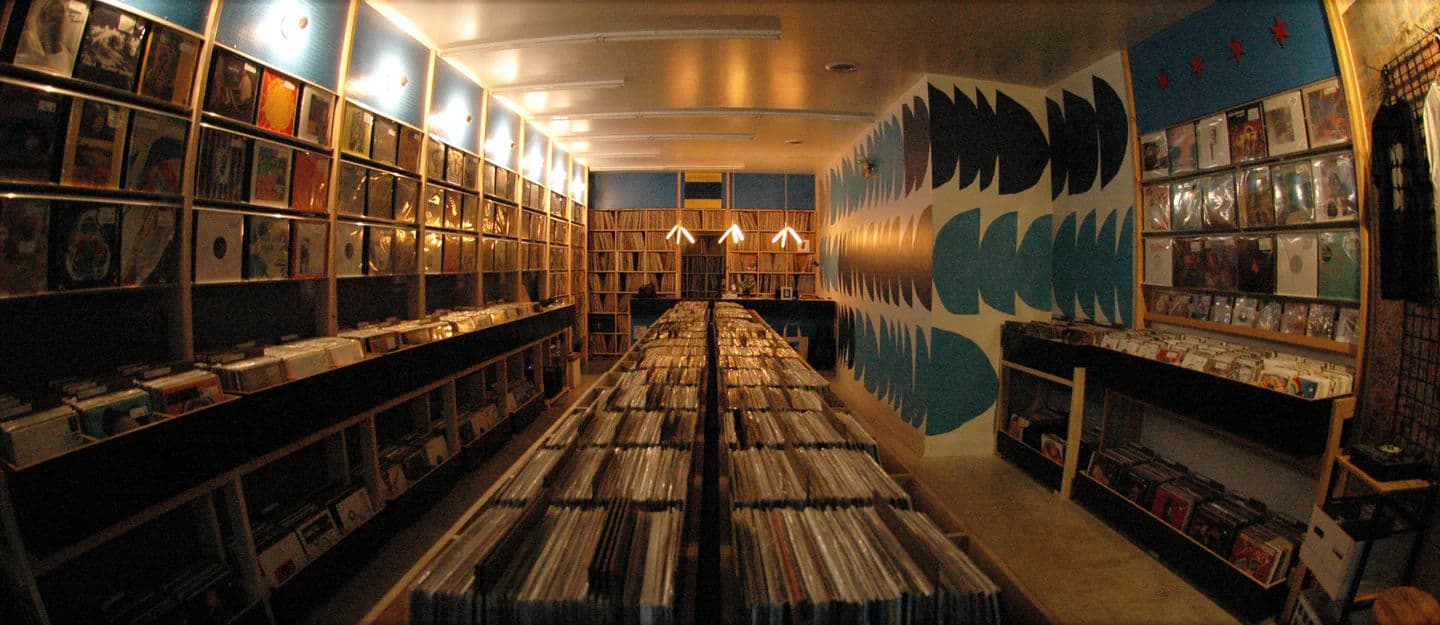 Inside 606 Records in Chicago, narrow shop with rows of vinyl records in bins and colorful wall art with album covers displayed.