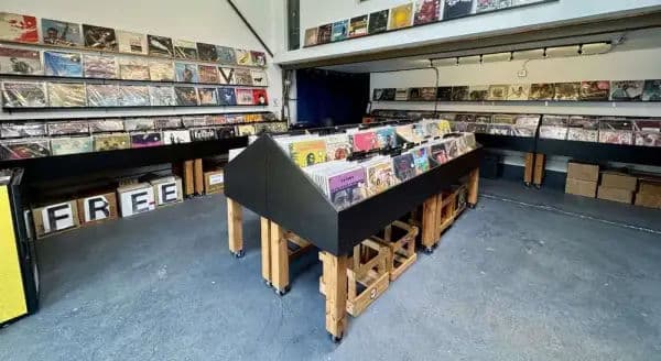Interior of a minimalist record store with black bins of vinyl records arranged on wooden stands.