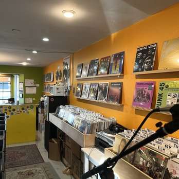 Interior of Love Wheel Records, a small record shop with orange and green painted walls.