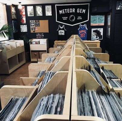 Interior of Meteor Gem record shop with wooden record bins and wall displays, customers browsing vinyl collections.