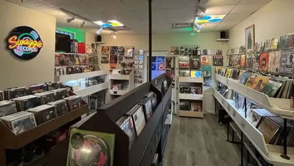 Interior of Swaggie Records with vinyl displayed along the walls, bins in the center, and a glowing neon sign that reads 'Swaggie Records.'