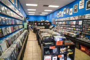 Oakland record store with long aisles of new/used vinyl, blue walls, and turntables on a center table.