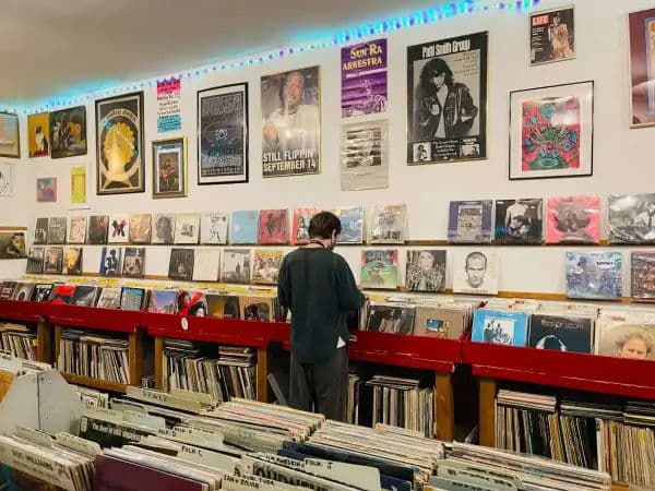 Interior of the Philadelphia Record Exchange showing long rows of vinyl bins with customers browsing, fluorescent lighting, and a casual warehouse vibe.