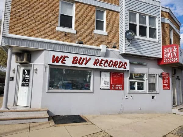Exterior of Sit & Spin Records in South Philly, featuring a bright red awning with the store name and an inviting window display of records.